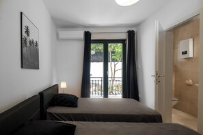 Habitación de hotel con dos camas, balcón con vistas, aire acondicionado y baño con dispensador de toallas.