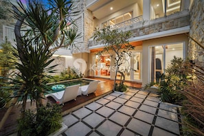 A modern house with a pool, outdoor seating, and a stone facade. - Agie Villa by Kozystay - Canggu (Canggu)