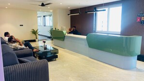 Ein Hotel-Rezeptionsbereich mit moderner Rezeption, Sitzgelegenheiten inklusive Sofas und einem großen Fenster, das für natürliches Licht sorgt.
