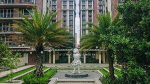 A residential building with multiple balconies, a central fountain, and surrounding greenery.