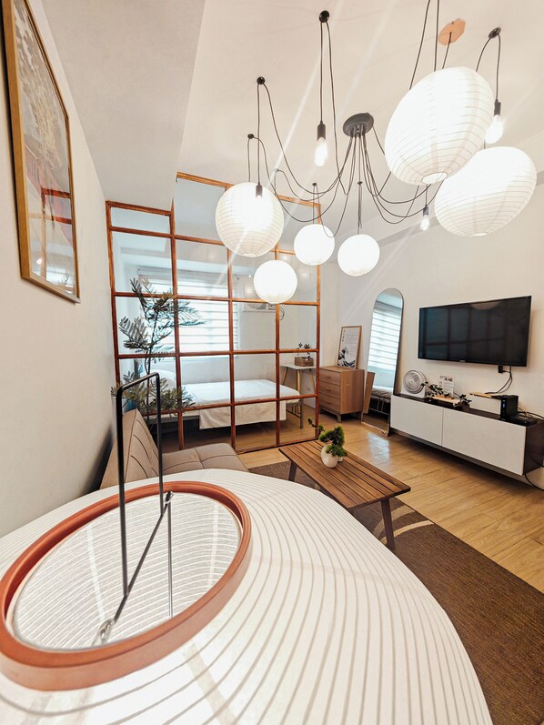 Un salon moderne avec une grande fenêtre, un canapé, une table basse et un téléviseur.