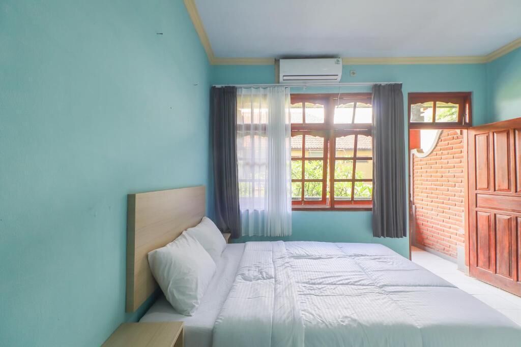 A bedroom with a bed, a window with curtains, and a brick wall.