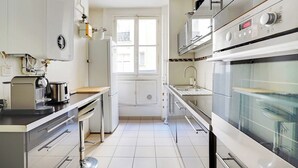 Une cuisine moderne équipée d’un four encastré, d’une machine à café et d’une fenêtre offrant une belle vue.
