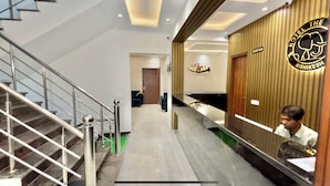 A hotel reception area with a reception desk, a staircase, and a reception sign. - Hotel The Tusk (Rishikesh)
