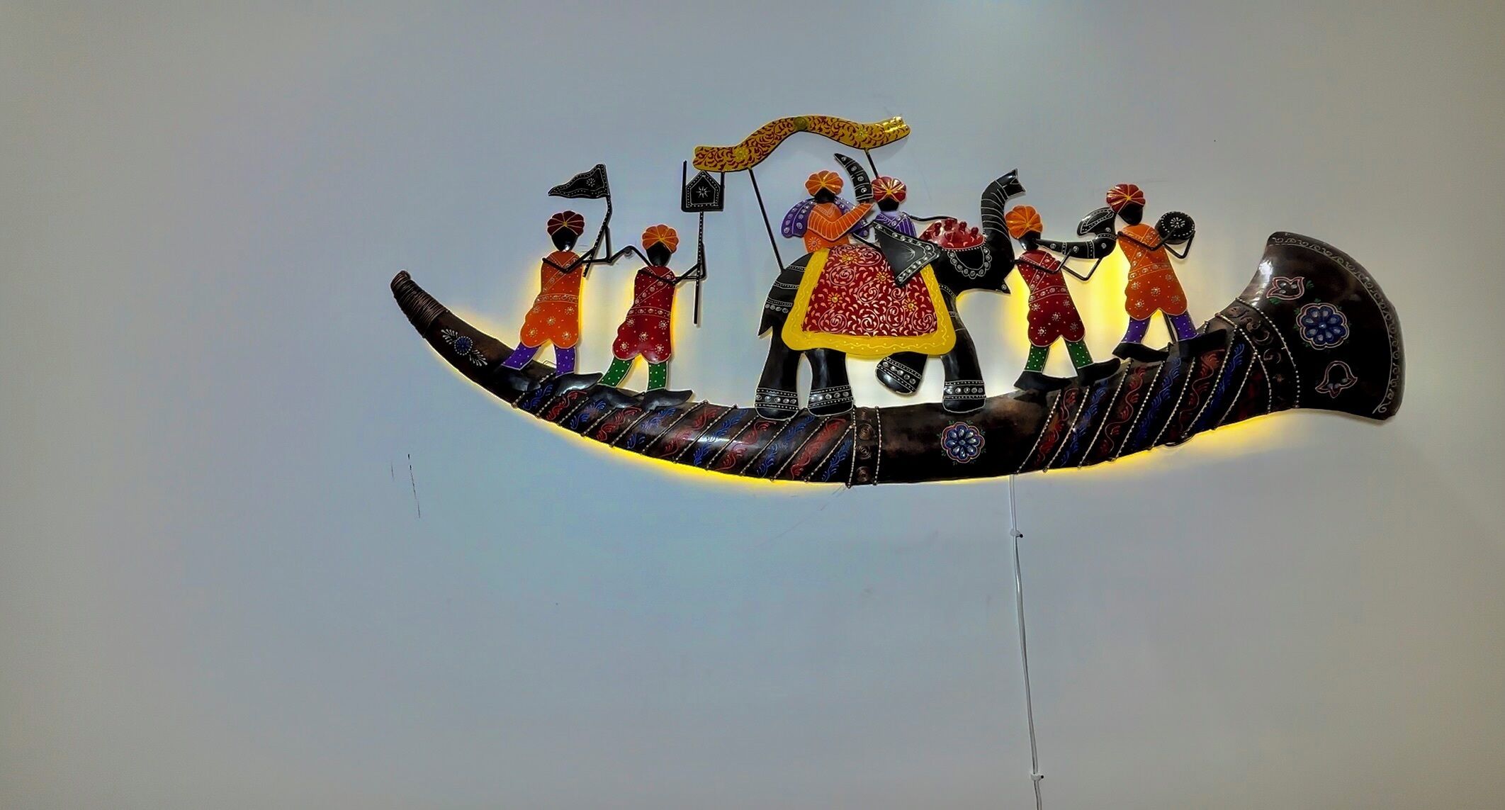 A decorative wall piece featuring a stylized boat with figures in traditional attire.