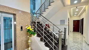 A modern interior with a marble staircase, a vase of yellow flowers, and a clean, well-lit hallway. - Hotel The Tusk (Rishikesh)
