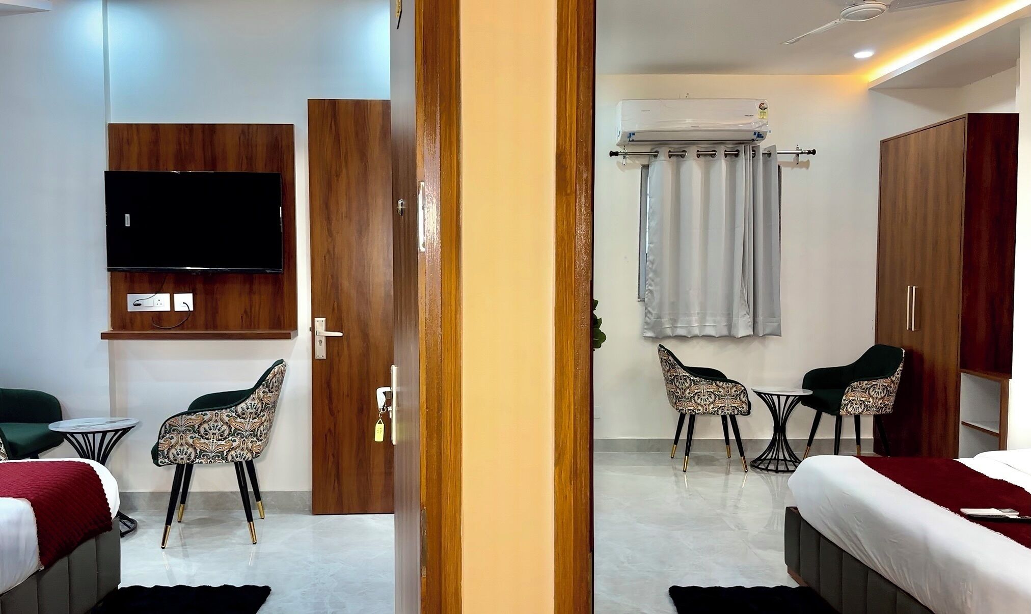 Habitación de hotel con cama, televisor montado en la pared, escritorio con sillas y armario.