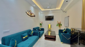 A modern living room with teal sofas, a coffee table, and decorative vases. - Hotel The Tusk (Rishikesh)