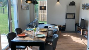 A modern dining area with a wooden table, black chairs, and a built-in TV. - Riedlodge Lake Constance-Upper Swabia Holiday Home (Guggenhausen)