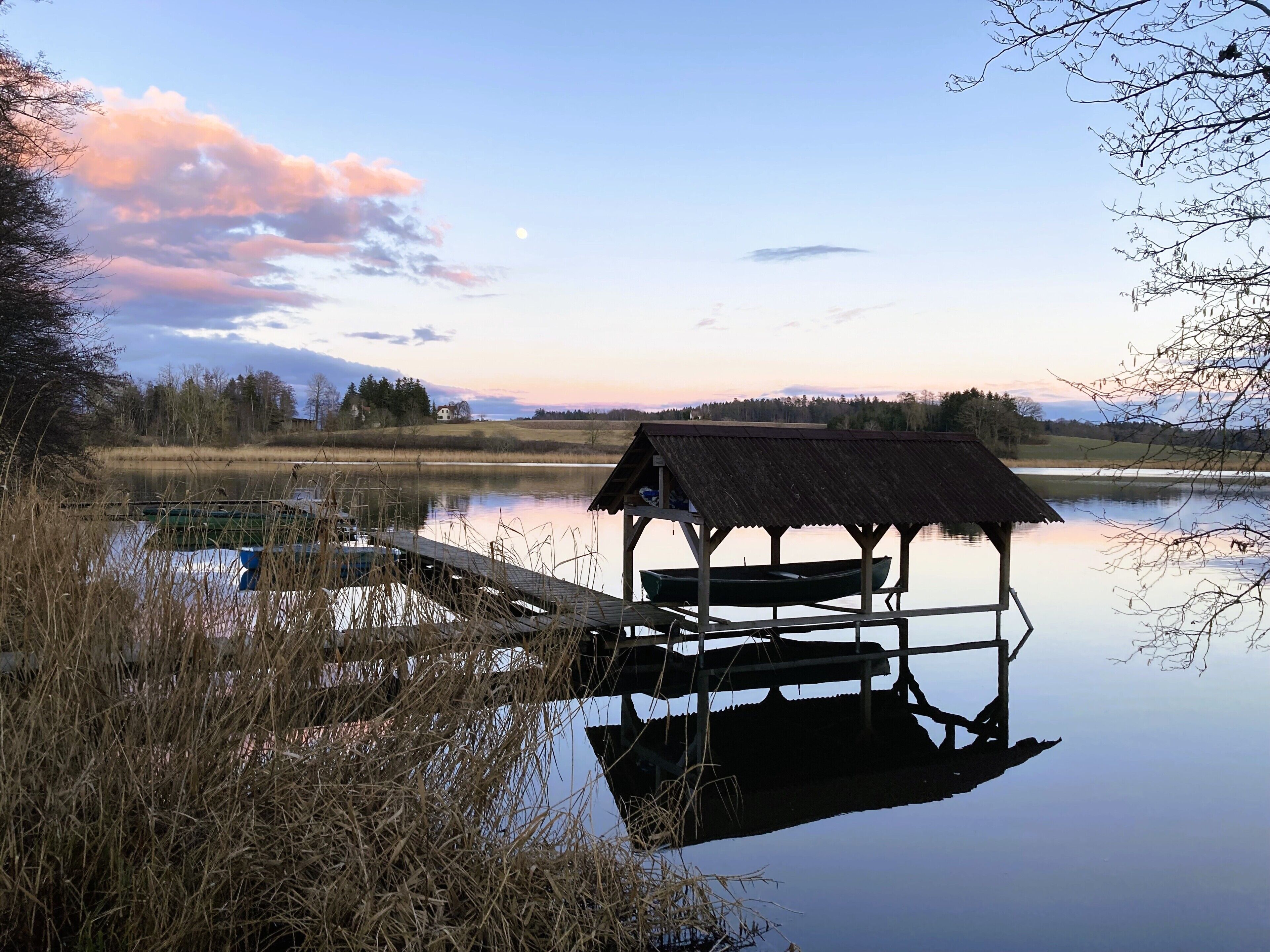 Un paysage paisible au bord du lac, avec un quai en bois et une petite cabane.