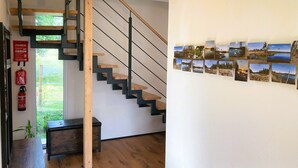 A staircase with wooden steps and metal railings, a wall with photographs, a fire extinguisher, and a bench. - Riedlodge Lake Constance-Upper Swabia Holiday Home (Guggenhausen)