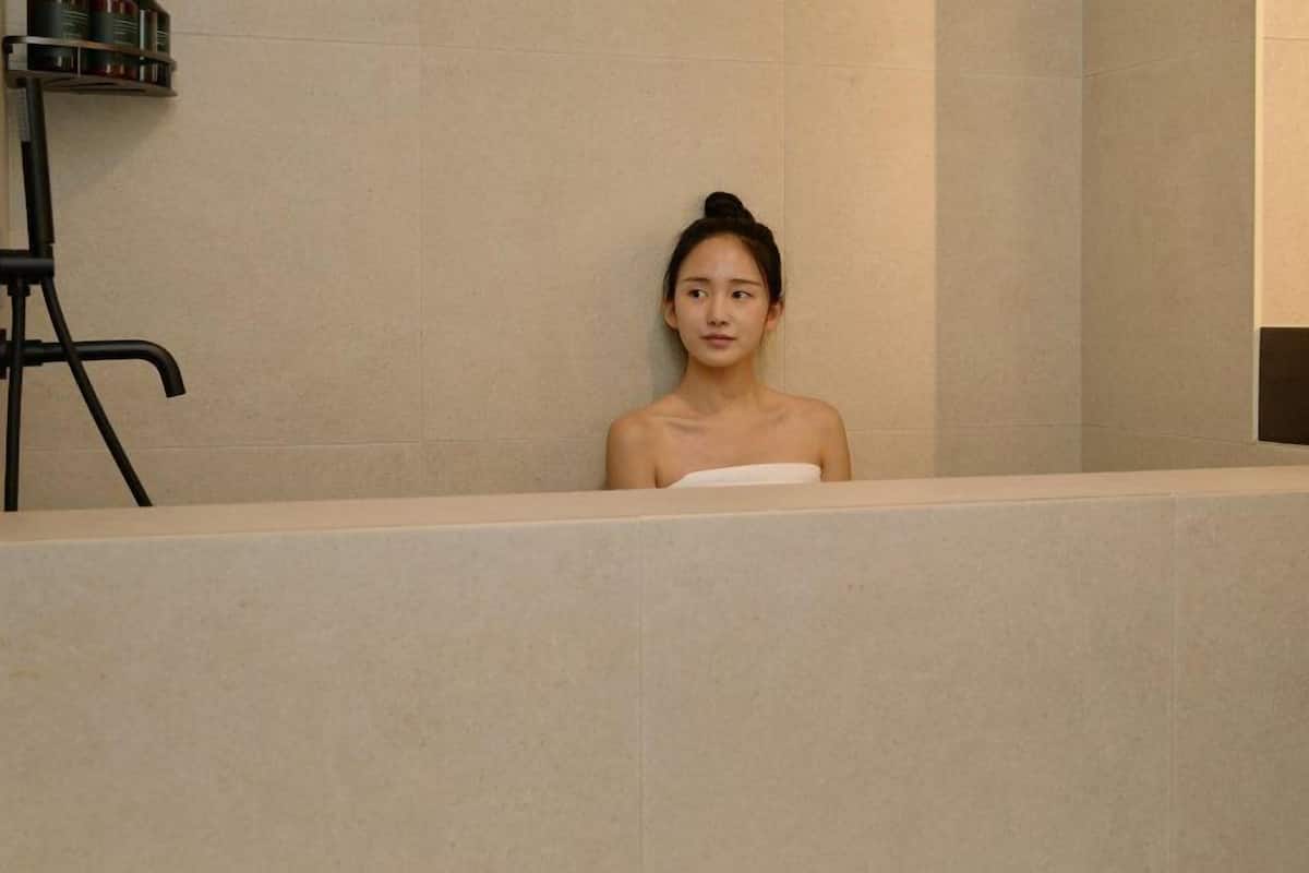 Eine Person liegt in einer Badewanne, umhüllt von einem Handtuch.