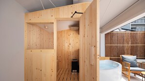Una sauna de madera con un banco, una mesita y una bañera de hidromasaje.