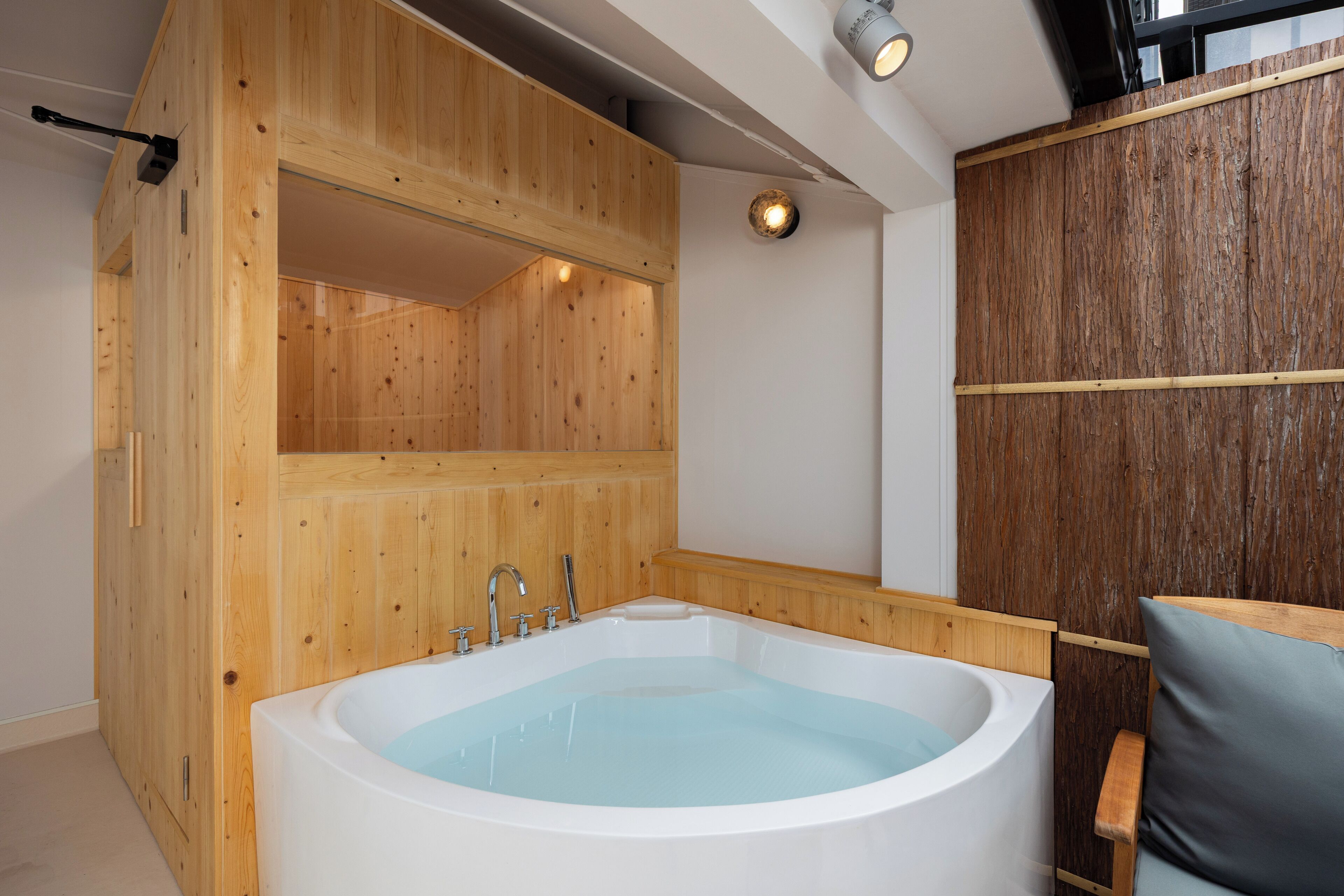 Une salle de spa en bois, dotée d’une grande baignoire, de murs en bois et d’un banc en bois.