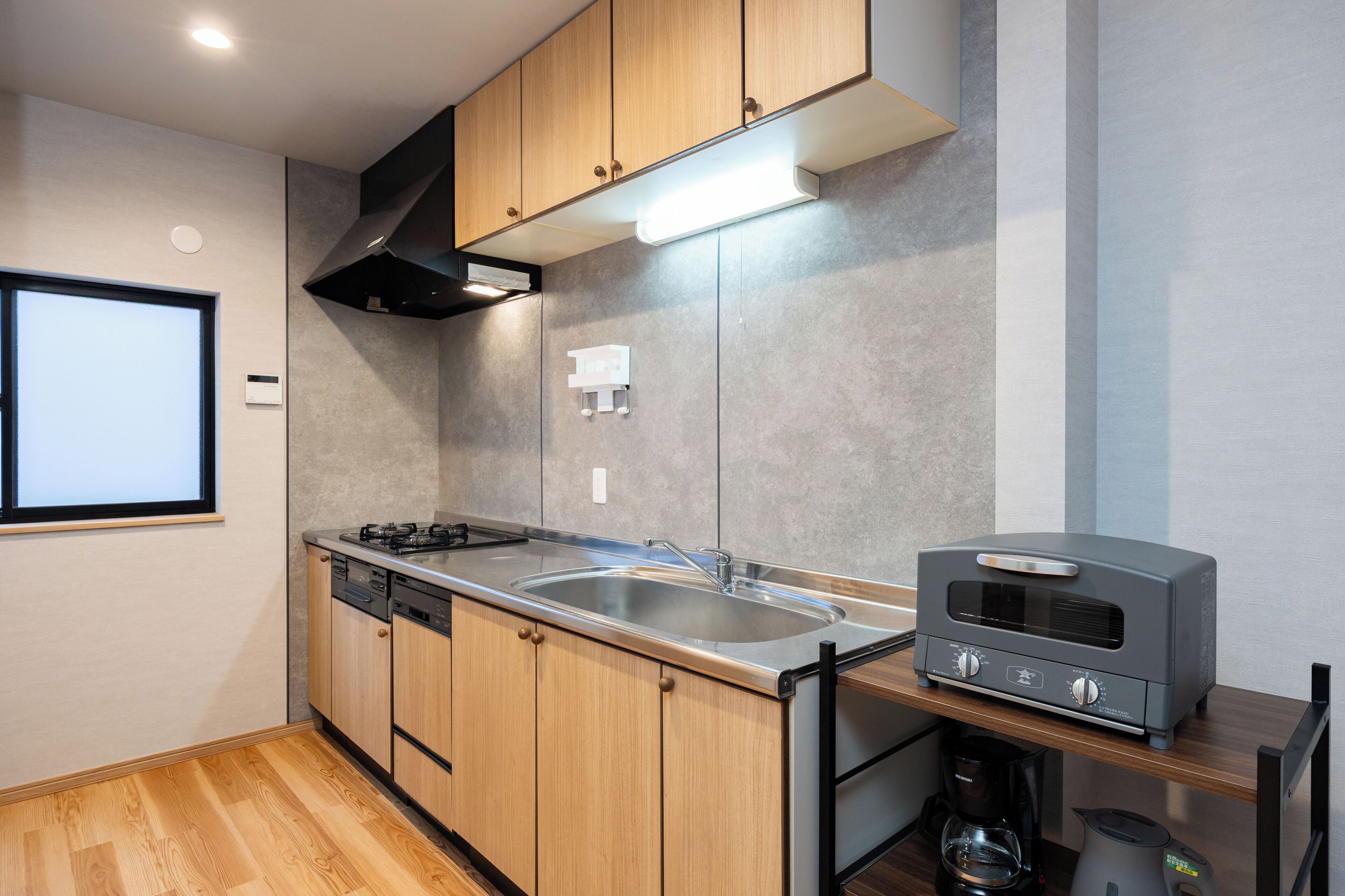 A modern kitchen with wooden cabinets, a stainless steel sink, a built-in oven, and a coffee maker.