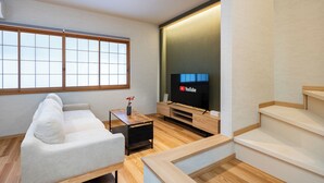 Una sala de estar moderna con un sofá, un televisor y una escalera de madera.
