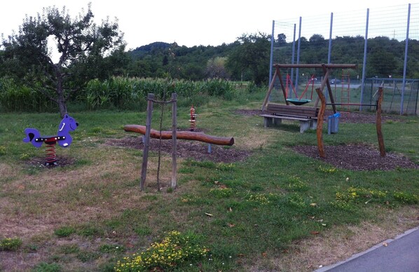 A playground with a swing set, a seesaw, and a slide.