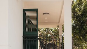 Un bâtiment moderne doté d’un balcon en verre, d’un escalier et de mobilier d’extérieur.