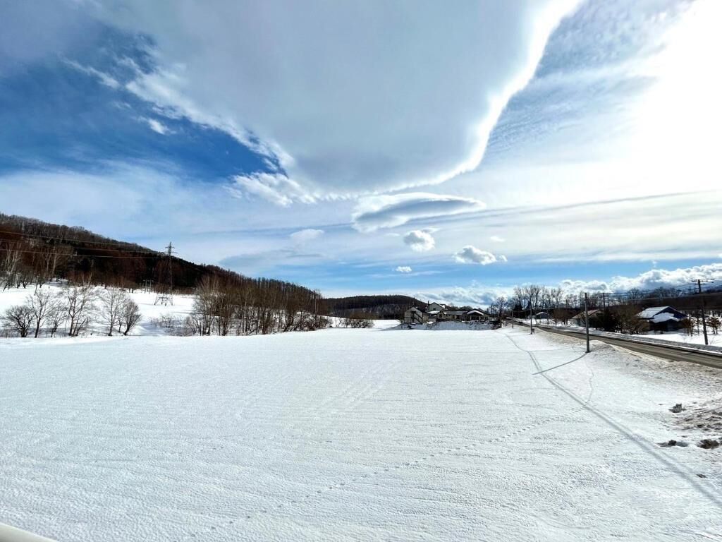 Ett snötäckt landskap med en klar himmel, en väg och byggnader i fjärran.