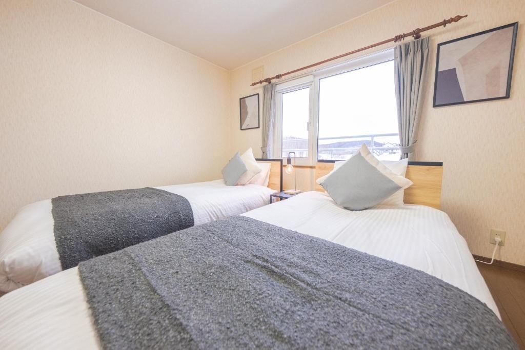 A hotel room with two beds, a large window, and a view of the sea.