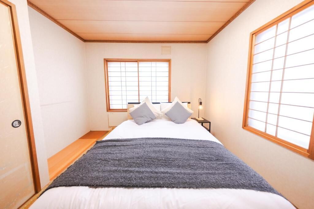 A bedroom with a bed, a window, and a bedside table.