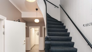 Un escalier avec une rampe noire et une pancarte indiquant « RÉCEPTION ».