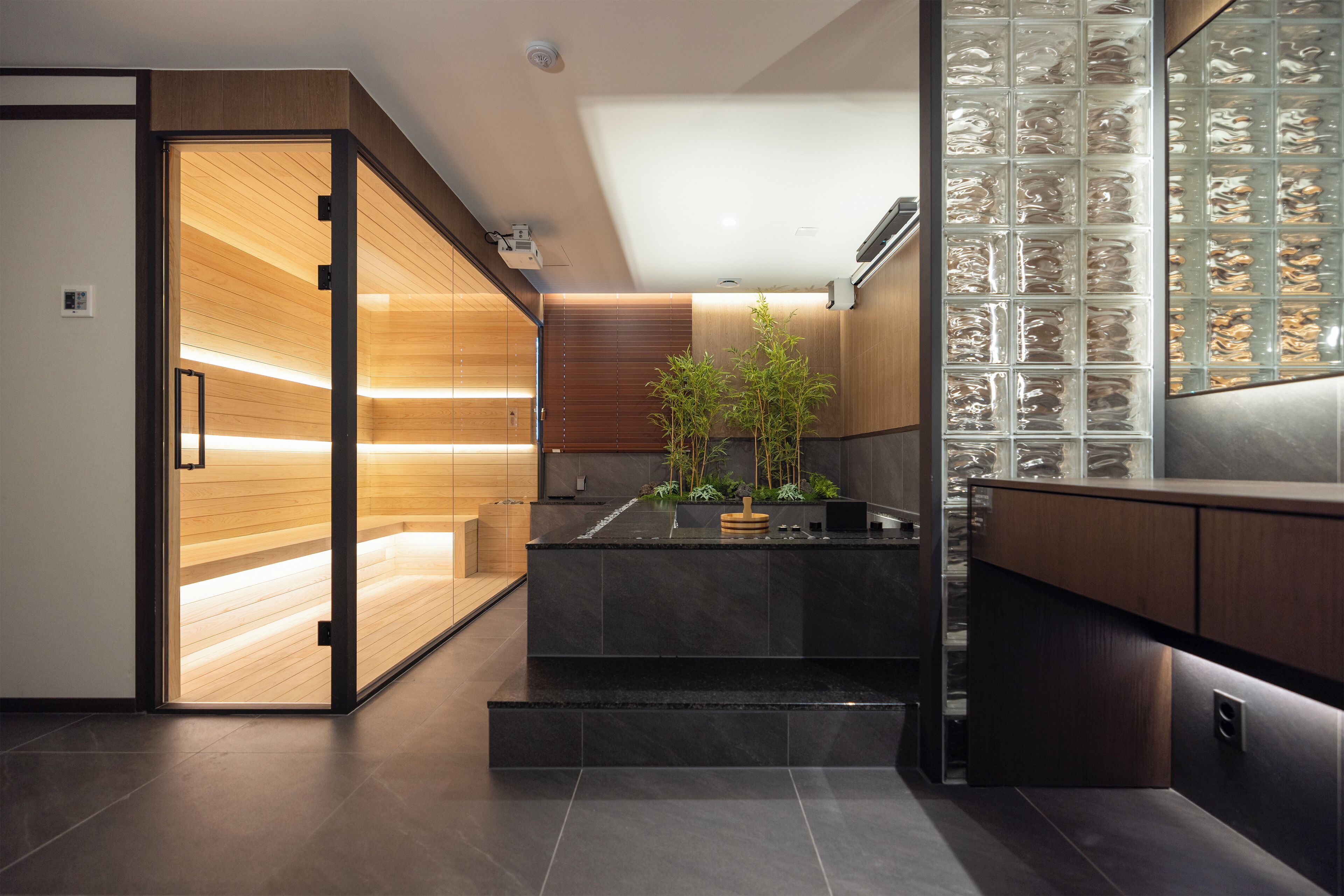 A modern kitchen with a wooden interior, a black countertop, and a glass display case.