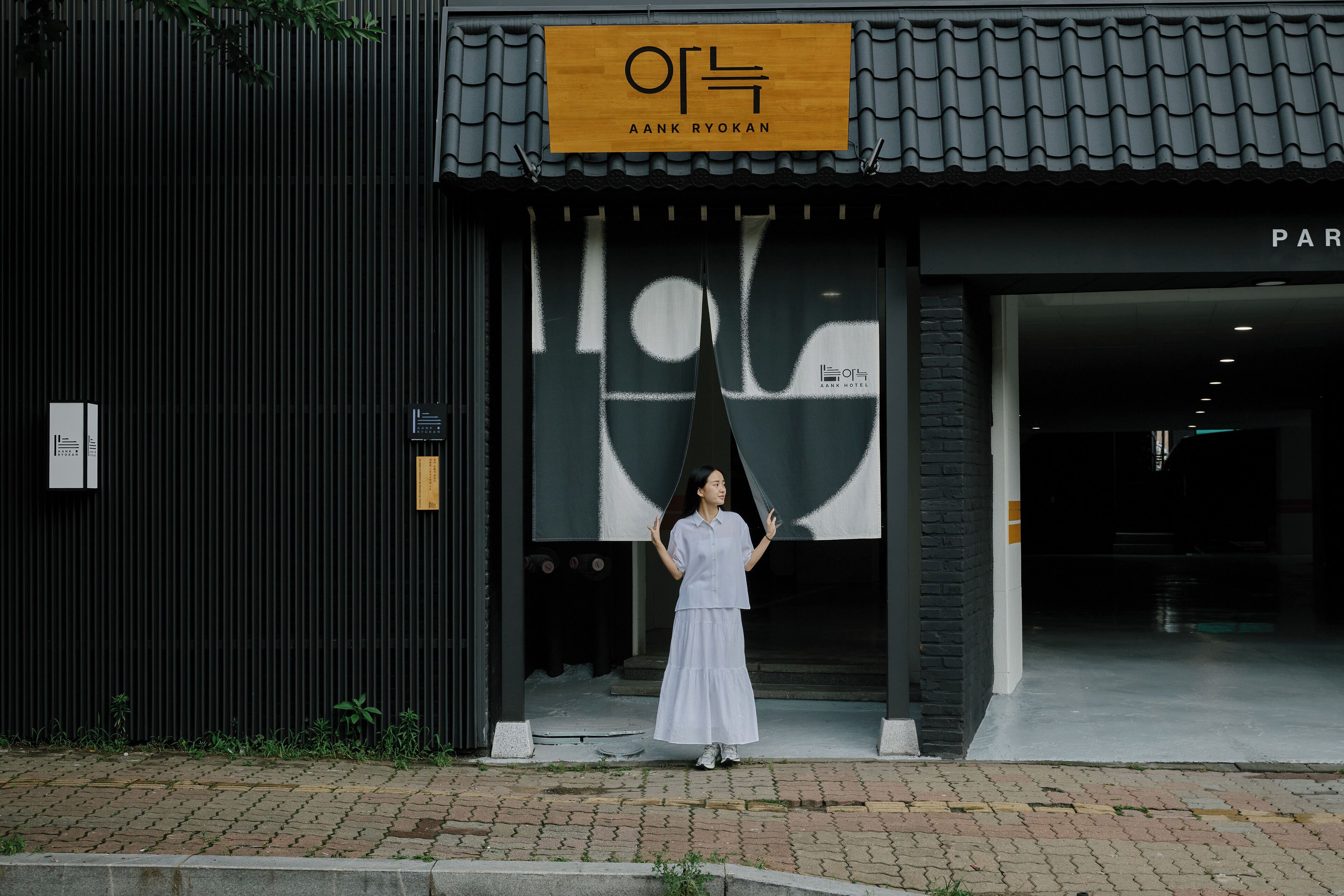 A hotel entrance with a large signboard and a person standing in front.