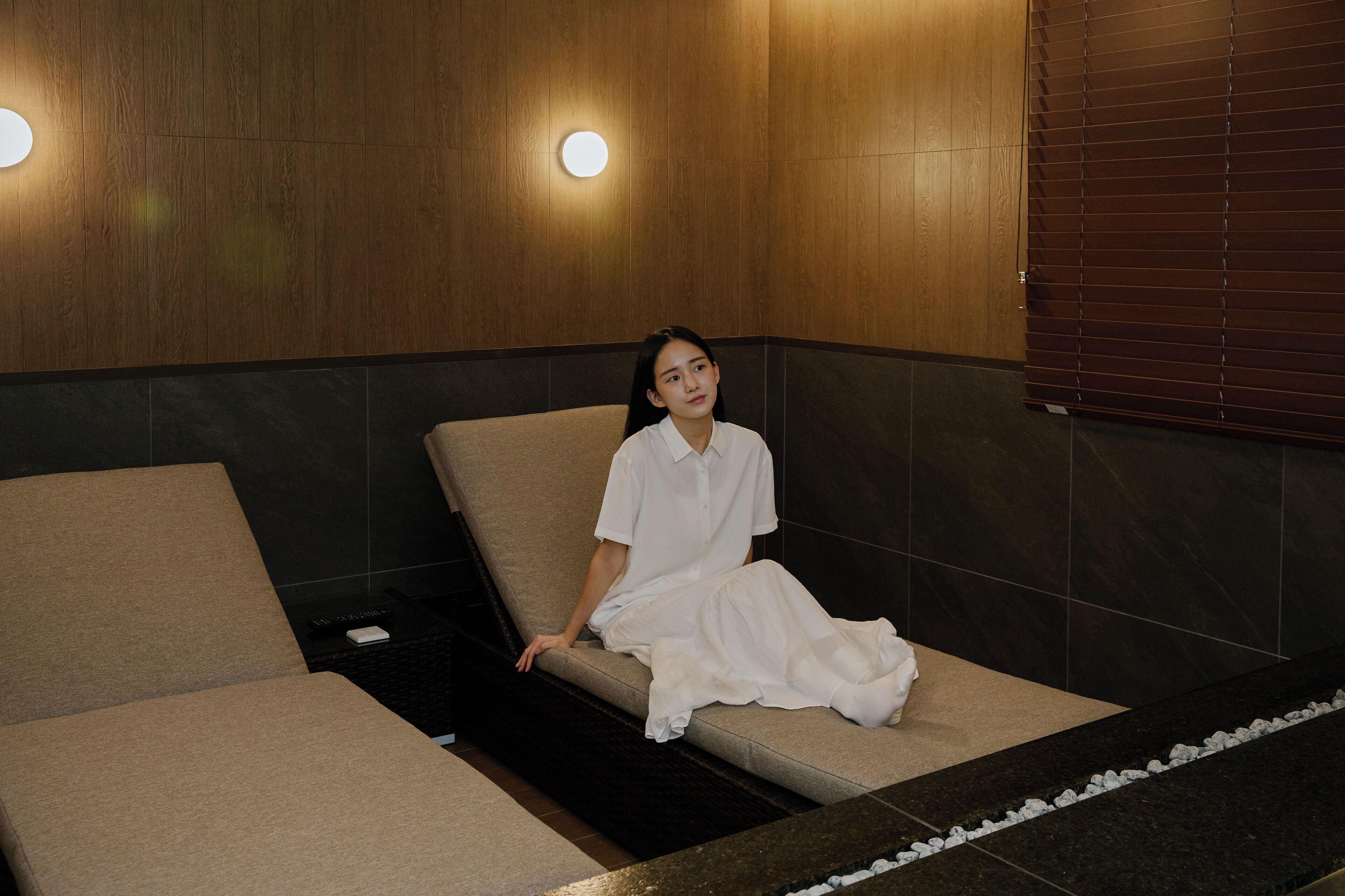 Ett spa-rum med en väggpanel av trä, en massagebänk och en bänk.