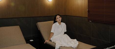 A spa room with a wooden wall, a massage table, and a bench.