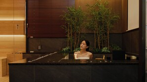 A spa area with a wooden reception desk, bamboo plants, and a modern design. - Anook Ryokan Hotel Suwon (Suwon)