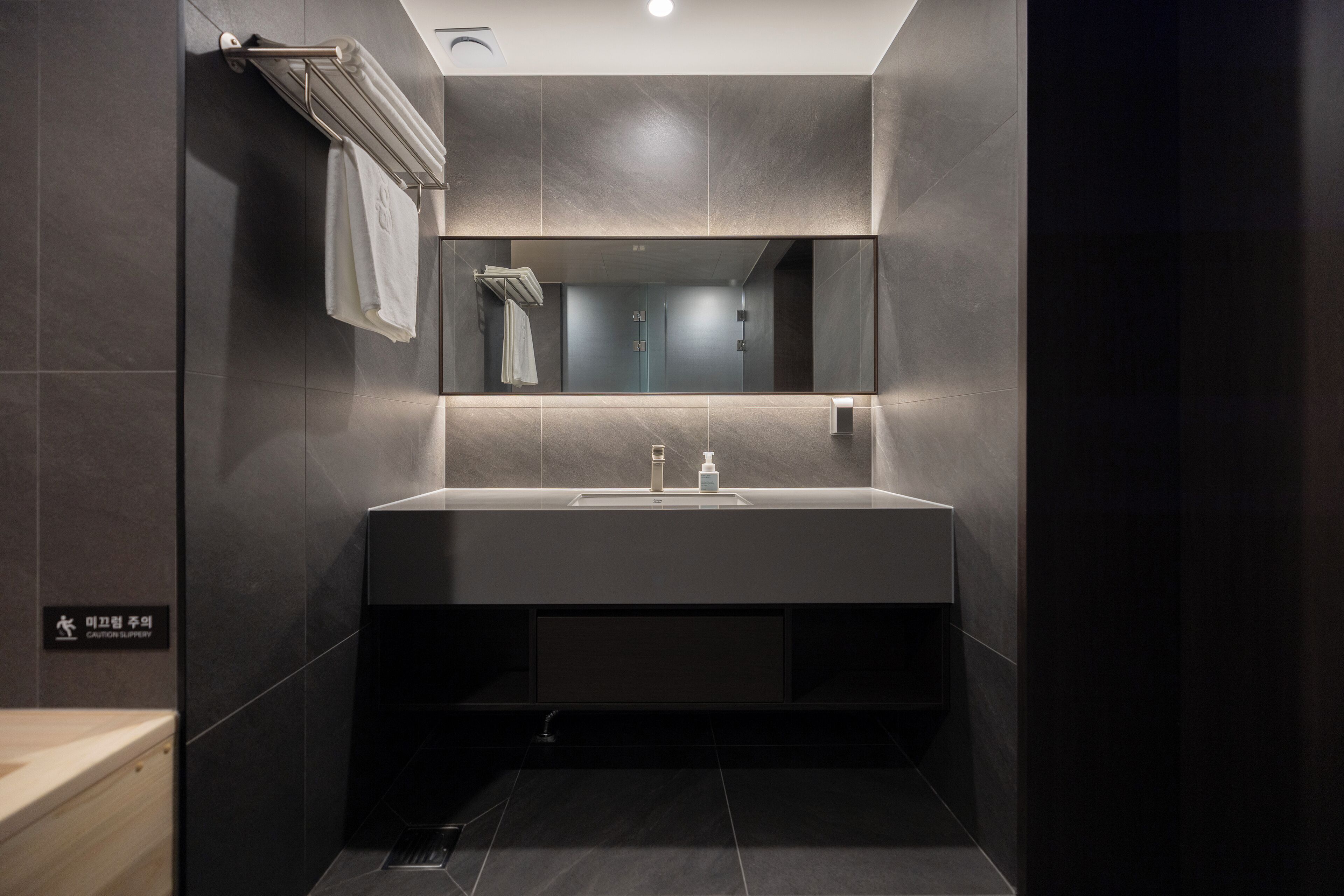 Un baño moderno con un espejo grande, un lavamanos y un perchero para toallas.