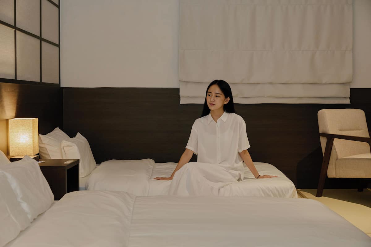A hotel room with a large bed, a bedside table with a lamp, and a chair.