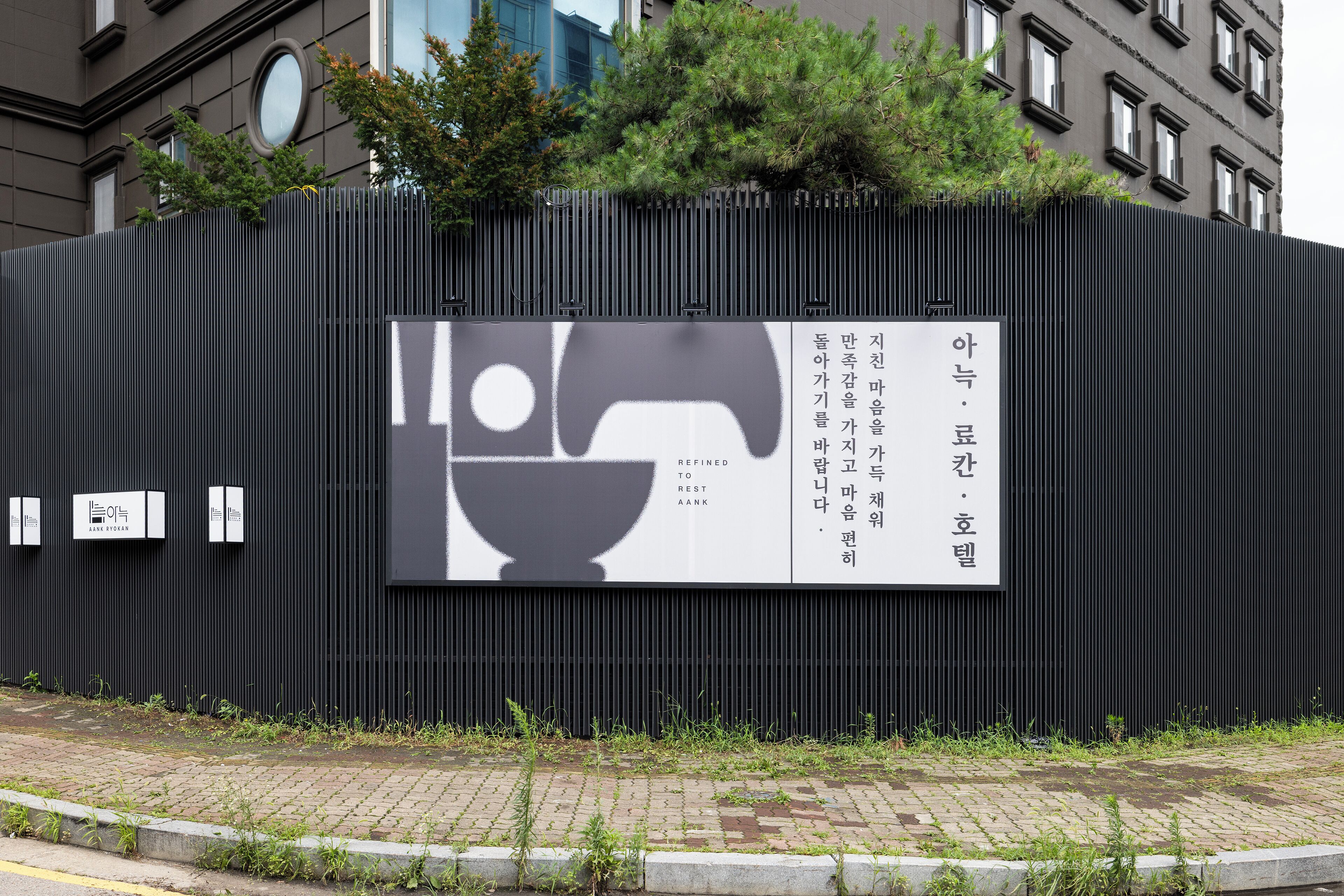 A black metal fence with a large billboard featuring a logo and text.