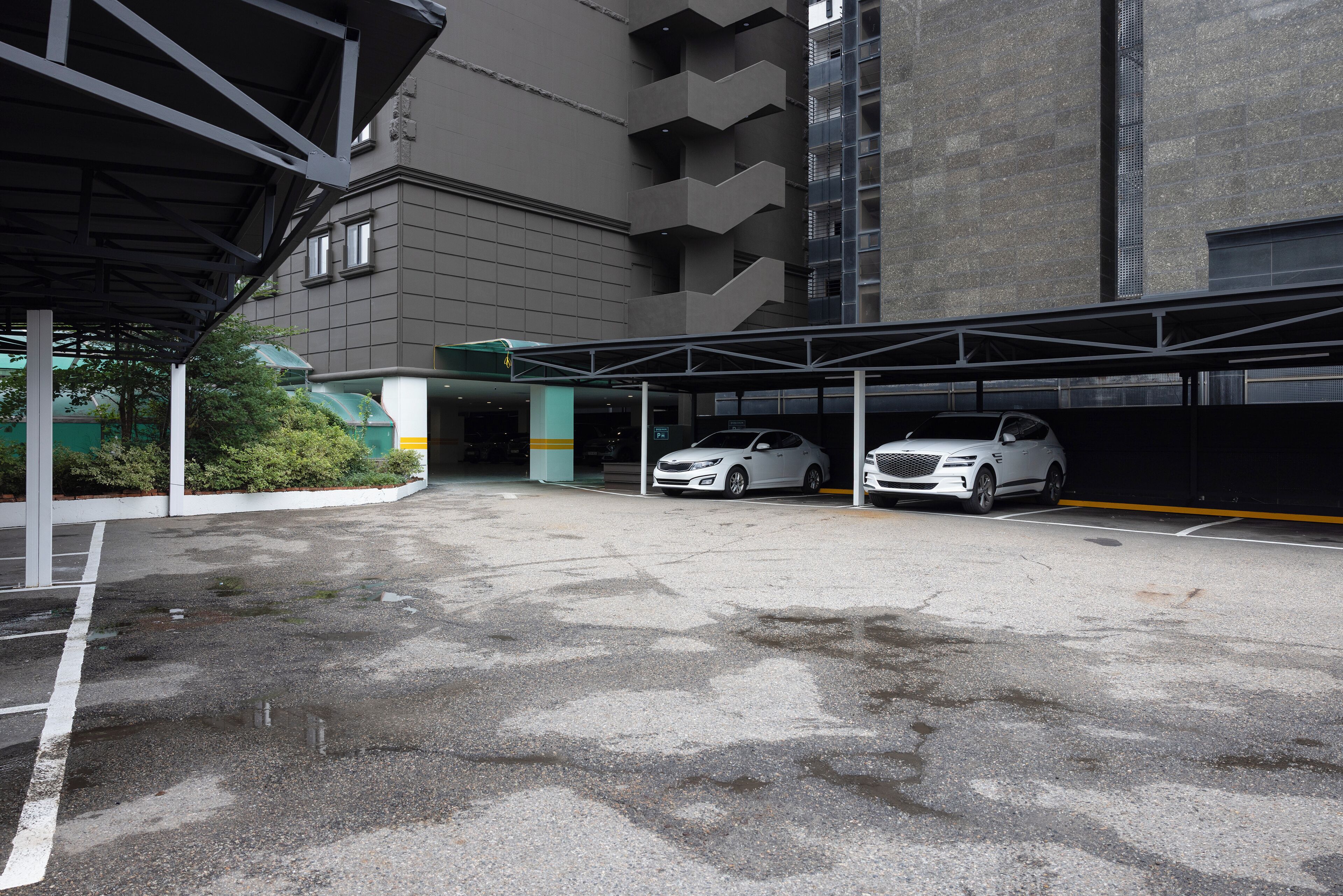 A parking garage with two white cars parked under a covered area.