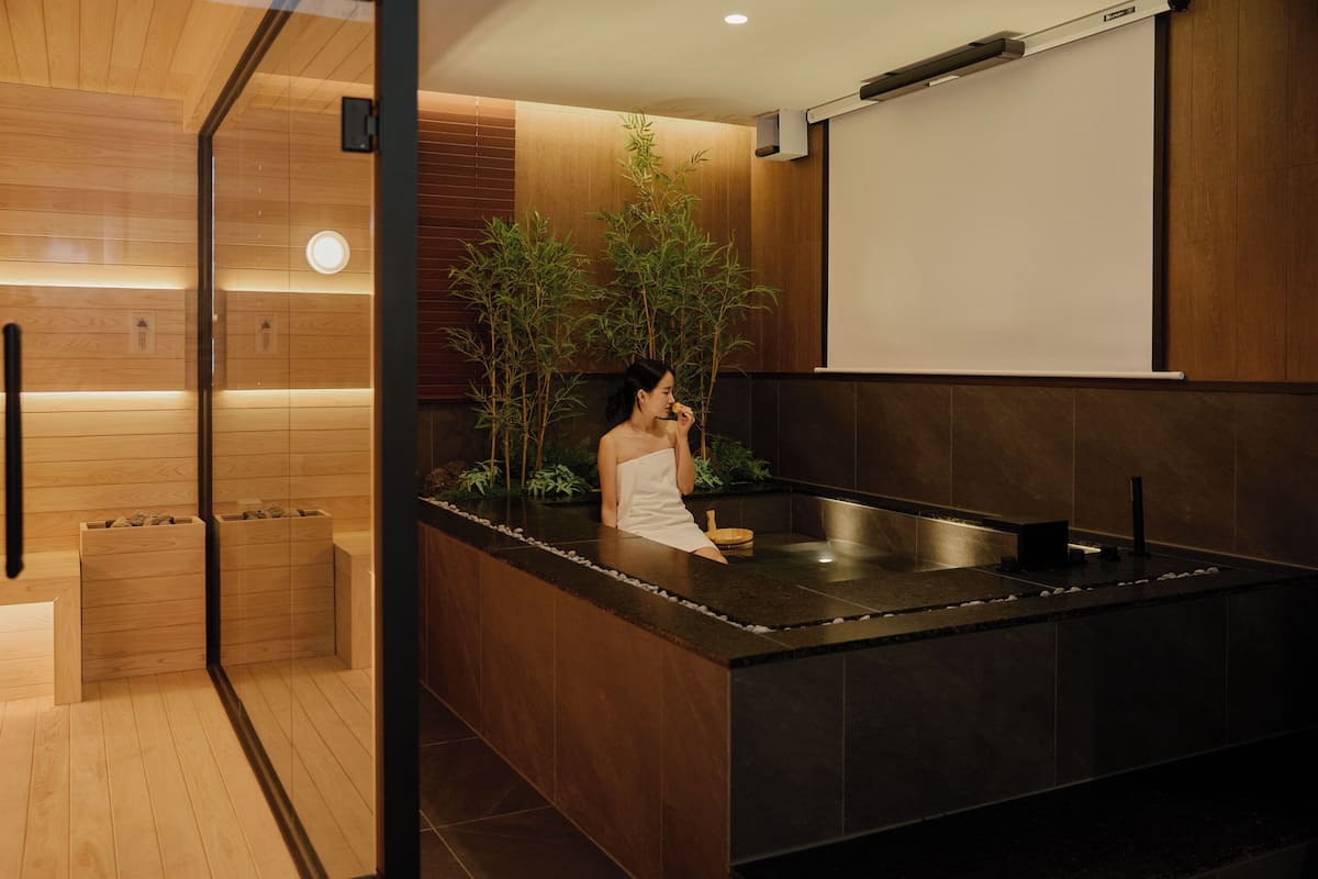 A modern spa area with a wooden floor, a heated stone bath, and a wooden panel wall.