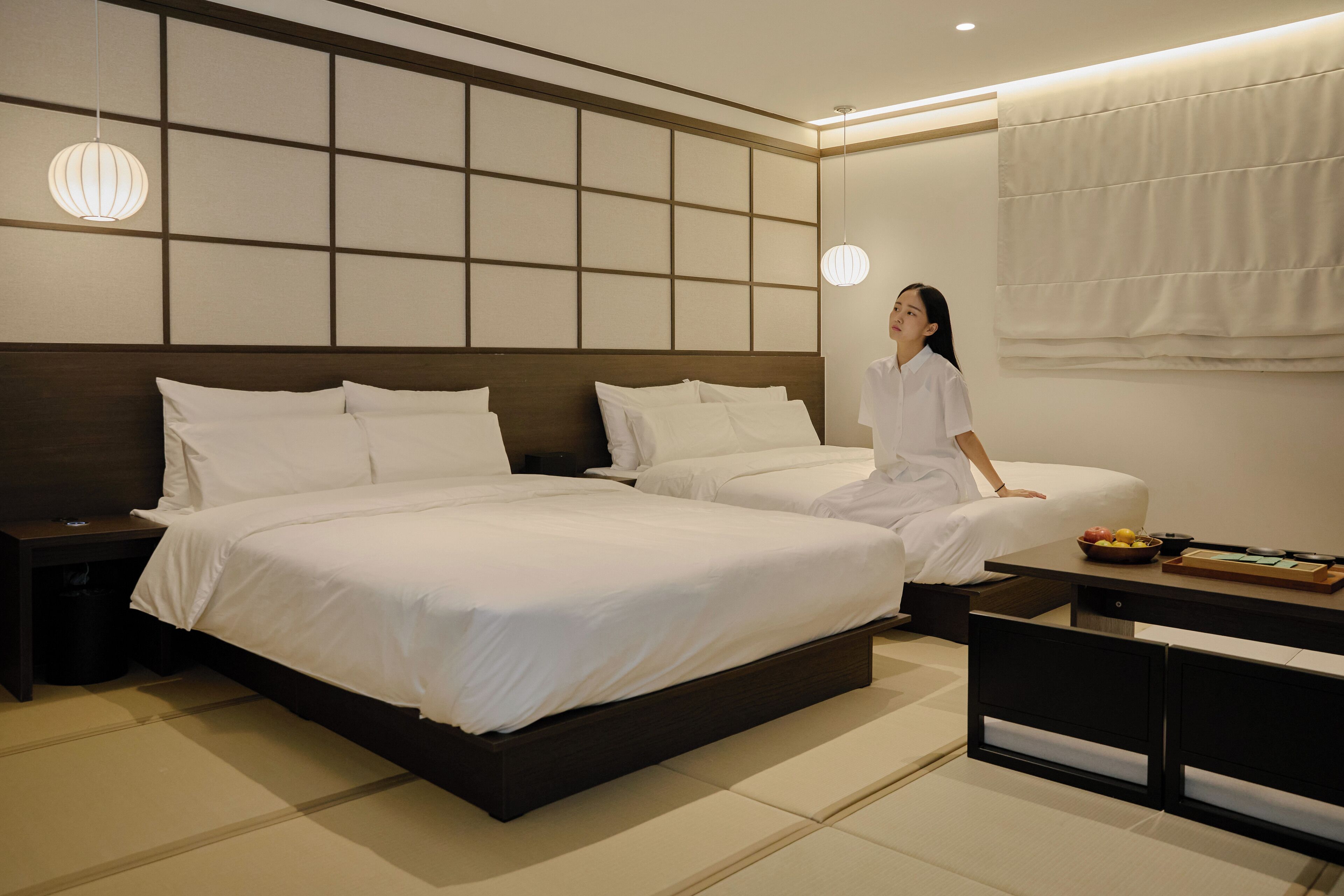 Ein modernes Hotelzimmer mit einem großen Bett, Nachttischen und einem kleinen Tisch mit Früchten.