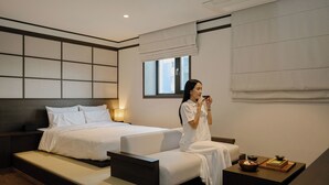 A modern hotel room with a large bed, a smaller sofa, and a bedside table with a bowl and tray. - Anook Ryokan Hotel Suwon (Suwon)