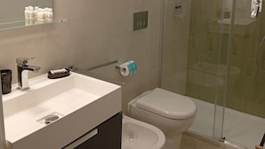 A modern bathroom with a glass-enclosed shower, a white sink with a mirror above it, and a toilet. - Borgo Sant'Antonio 14B (Siracusa)