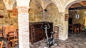 A rustic room with stone walls, wooden tables, and chairs, and an exercise bike. - Apartment in Modigliana with swimming pool (Modigliana)