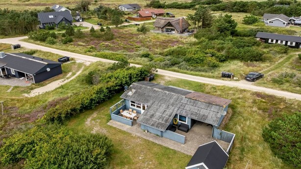 Een kustpand met meerdere huizen, een groot gazon en uitzicht op zee.