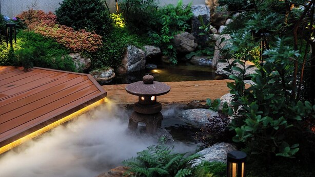 A serene garden with a wooden deck, a stone lantern, and a small pond surrounded by rocks and greenery. - Qi Yi Nanxu Pavilion Homestay (Kunming)