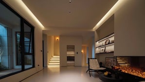 A modern living room with a fireplace, a staircase, and a large window. - Qi Yi Nanxu Pavilion Homestay (Kunming)