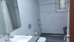 A bathroom with a white sink, a toilet, and a shower area. - HOTEL SHHAURYA  (New Delhi)