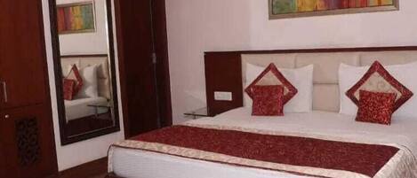 A bedroom with a large bed, wooden headboard, and a mirror on the wall.