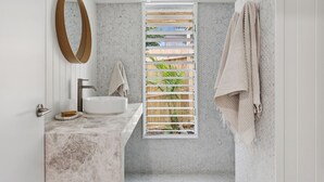 A bathroom with a white sink, a wooden-framed window, and a towel rack.