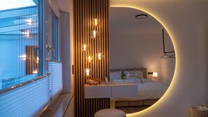 A modern bedroom with a curved wall, a bedside table, a bed, and a window with blinds. - VILLAFINE - Exclusive villa with pool & sauna in Vaihingen an der Enz (Aurich, Vaihingen an der Enz)