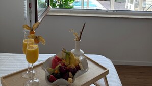 A room with a bed, a tray with fruit and a drink, and a window with a view of a pool and greenery outside. - VILLAFINE - Exclusive villa with pool & sauna in Vaihingen an der Enz (Aurich, Vaihingen an der Enz)