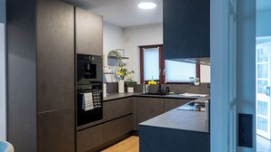 A modern kitchen with a built-in oven, microwave, and a large island with a sink. - VILLAFINE - Exclusive villa with pool & sauna in Vaihingen an der Enz (Aurich, Vaihingen an der Enz)