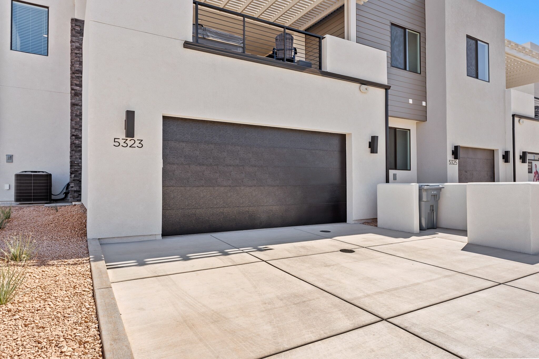 A modern building with a large garage door, numbered 5323, and a clean, minimalist design.
